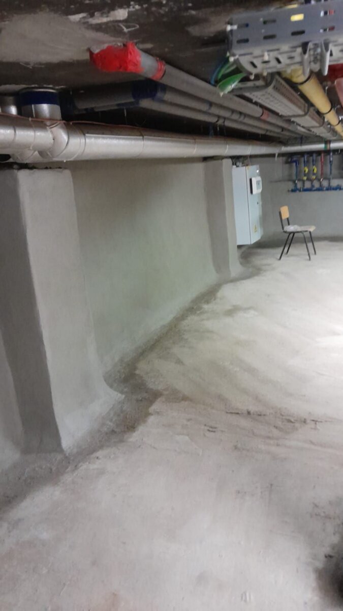 Afgedichte kelderwand onder de leidingen