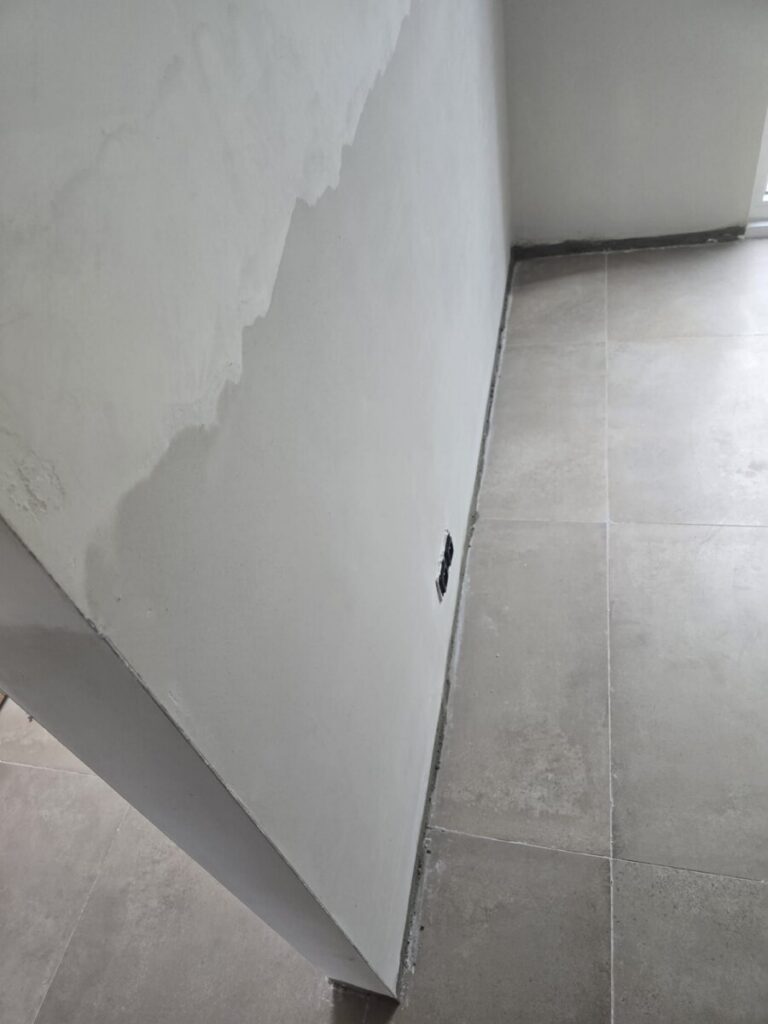 Nieuwe tegelvloer langs een herstelde muur