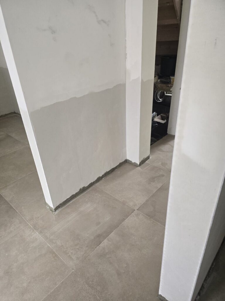 Gang met vernieuwde pleister onderaan de muur na vochtbehandeling