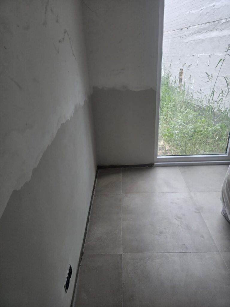 Herstelde muur naast een glazen deur na vochtbehandeling